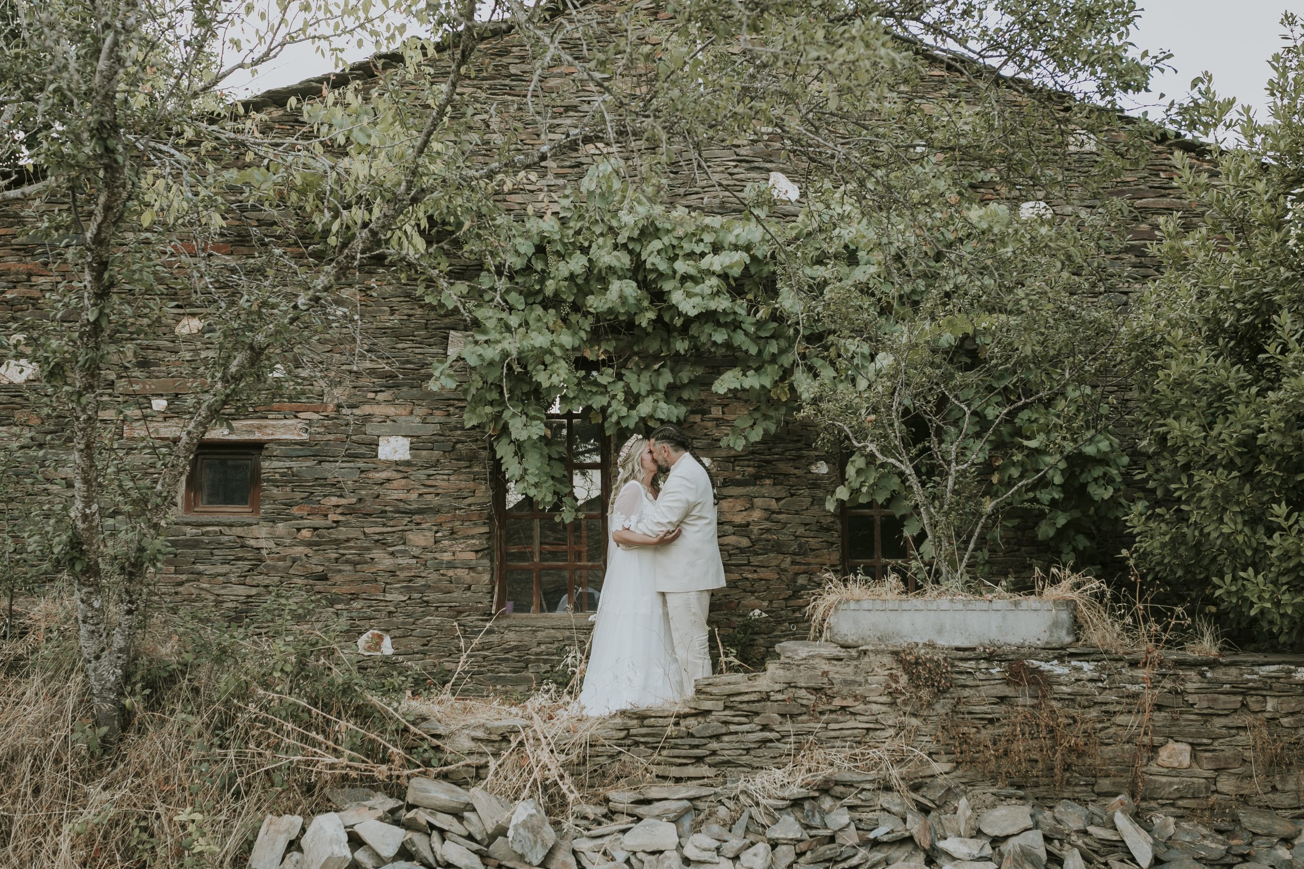 Pareja de novios besándose frente a una casa tradicional de piedra en Aldea Tejera Negra, boda íntima en entorno natural